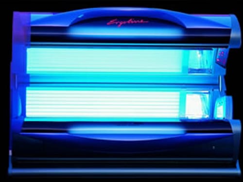 A blue light is shining on the back of a tanning bed.